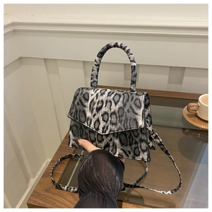 Detail showing grey leopard print crossbody bag with trapezoid structure and top handle