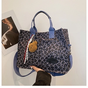Detail of leopard print canvas tote with leather logo tag and plush bear charm