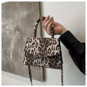 Detail of leopard print handbag showing grainy texture and magnetic flap closure