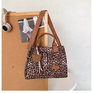 Detail of leopard print canvas tote with plush bear charm and brown nylon straps