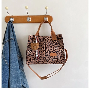Detail view of leopard print canvas tote bag with shoulder strap and plush bear charm