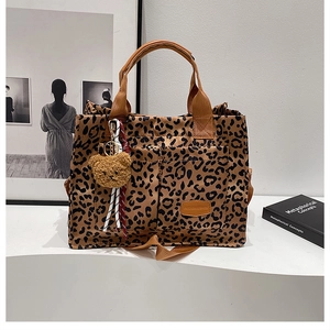 Detail of leopard print tote bag featuring front pockets, bear charm, and striped ribbon decor