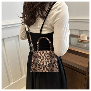Detail of leopard print crossbody bag with silver hardware on model in urban setting