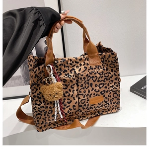 Close-up of leopard print canvas tote bag with brown bear charm and adjustable strap