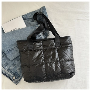 Detail of black quilted puffer tote bag with spacious interior and wide nylon handles
