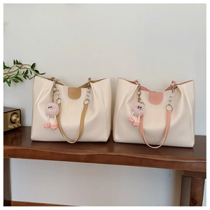 Detail of white PU leather tote bags with colorful straps, chain handles and plush charms