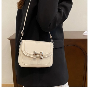 Détail du nœud argenté et des coutures sur le sac à bandoulière en cuir crème