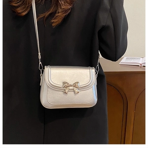 Detail of silver crossbody bag with metallic bow and elegant faux leather texture