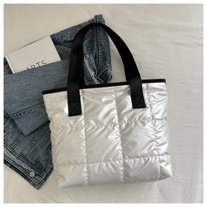 Detailed top view of a silver quilted tote bag with space cotton texture and arts book