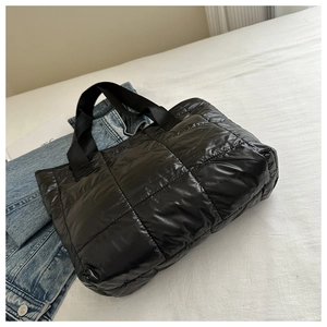 Detail of glossy black quilted nylon tote bag with thick padded square stitch patterns