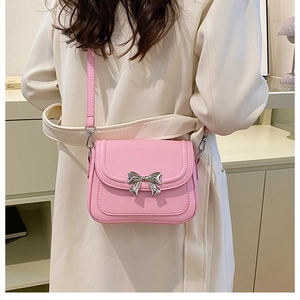 Detailed view of pink crossbody bag with silver metal bow clasp and smooth PU leather