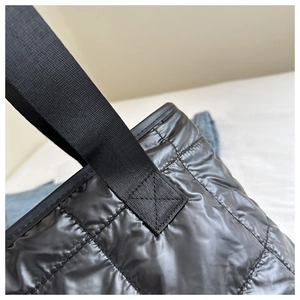 Detail of cross-stitch reinforced woven strap on black quilted nylon tote bag