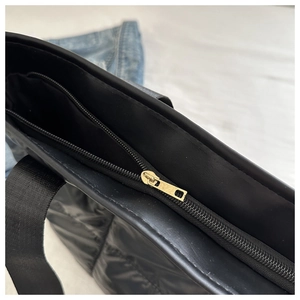 Detail of the golden metal zipper and quilted texture on a large black space cotton tote