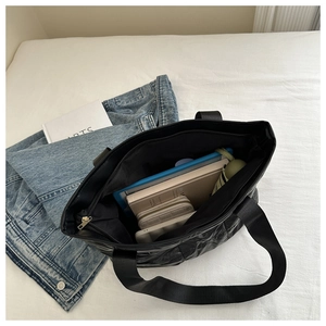 Large black quilted tote bag showing spacious interior with tablet, books and umbrella