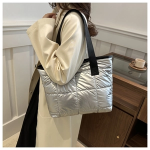 Close-up of silver quilted tote bag with metallic finish and black shoulder strap