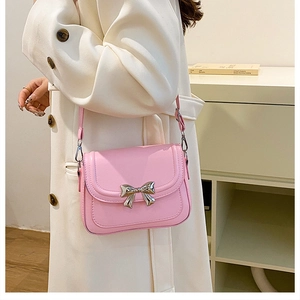 Detailed view of pink crossbody bag featuring a silver metal bow clasp and quilted stitching