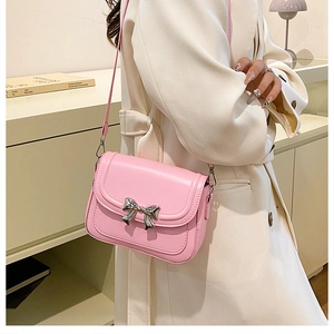 Detailed side view of pink crossbody bag with silver bow clasp and structured square shape