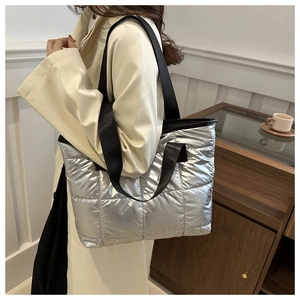 Detail of silver quilted tote bag featuring bold square stitching and wide black strap