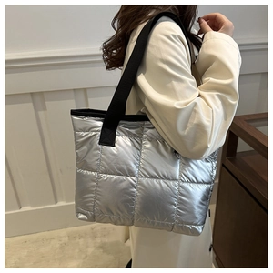 Detail of silver quilted tote bag with black strap showing metallic finish and large capacity