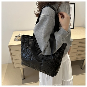 Close-up of black quilted nylon tote bag featuring a square pattern and wide webbing strap