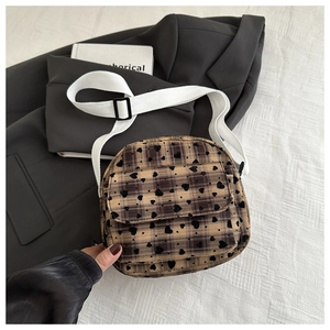 Detail of vintage plaid crossbody bag with black heart flocking and white canvas strap