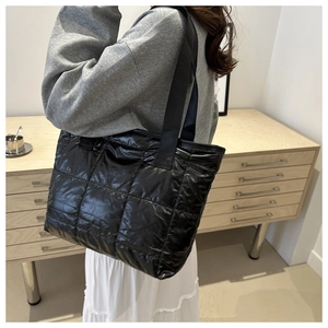 Detailed view of a black quilted tote bag showing padded texture and webbing straps