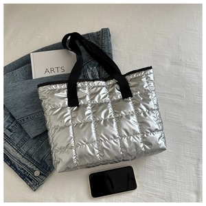 Chic silver quilted tote bag with black strap displayed with lifestyle accessories