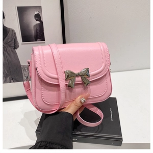 Detailed close-up of a pink crossbody bag featuring a metallic silver bow buckle detail
