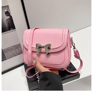 Détail du sac en similicuir rose avec nœud métallique argenté et fermeture à rabat