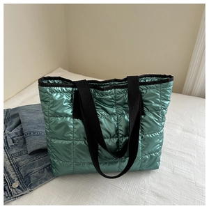 Detail of bright green quilted tote bag with metallic coating and black strap handles