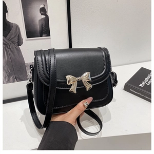 Détail du petit sac noir en cuir avec boucle en métal doré en forme de nœud