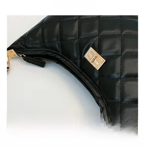 Close-up of golden metal twist lock and quilted black leather stitching on handbag