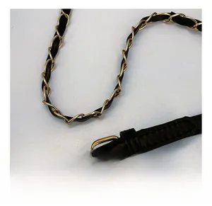 Detail of adjustable black leather strap with gold buckle and woven metal chain