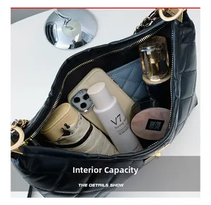 Top view of spacious interior of black quilted tote bag with phone and cosmetics