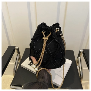 Détail du sac seau noir avec motifs matelassés effilochés et chaîne dorée à perles