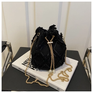 Détail du sac seau noir matelassé avec bords effilochés et perles sur le cordon