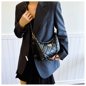 Close-up of quilted black crossbody bag with golden chain strap and turn-lock closure