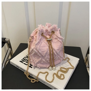 Détails du sac seau en denim rose avec bords effilochés, matelassage et cordon en perles