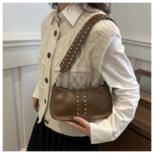 Sac à bandoulière marron vintage avec clous argentés porté par un mannequin