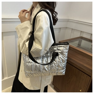 Detail of silver puffer tote bag with quilted metallic fabric and black shoulder strap