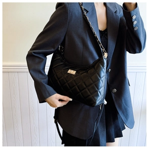Close-up of quilted black crossbody bag with metal twist lock and chain strap details