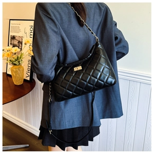 Quilted tote bag with golden chain straps shown on model in grey blazer outfit