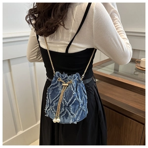 Détails du sac seau en denim avec motifs matelassés effilochés et chaîne dorée