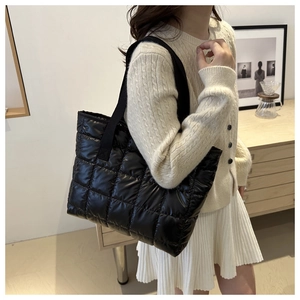 Close-up of black quilted tote bag showing embroidered stitching and puffy texture