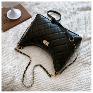 Close-up of black quilted hobo bag with gold metal turn-lock and chain strap detail