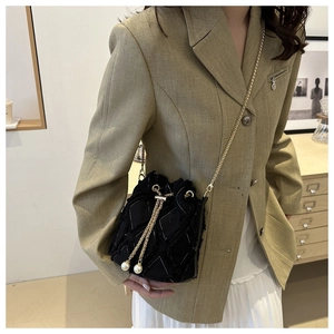 Détail du sac seau noir matelassé avec chaîne dorée et breloques en perles larges