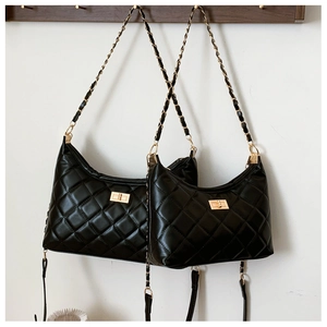 Detail of black quilted leather shoulder bag with gold chain strap and metal clasp