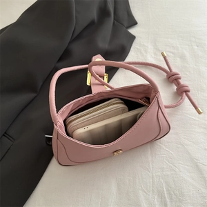 Sac à bandoulière rose minimaliste avec sangle nouée et boucle en métal sur tissu blanc
