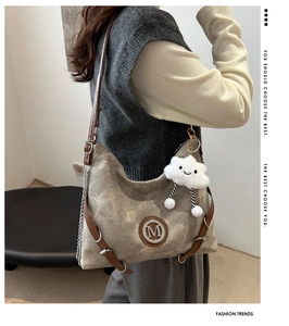 Detail view of vintage canvas crossbody bag with M logo and plush cloud charm