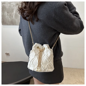 Detail of cream denim bucket bag with frayed quilted patterns and pearl chain drawstring